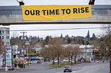 Two Sunrise Movement PDX activists display a banner which says “OUR TIME TO RISE”