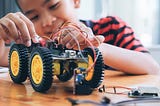 Concentrated boy creating robot at lab