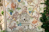 A picture of a fountain with monkeys painted on the tiles.