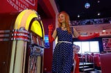 A woman dancing in front of a jukebox