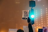 A person holding a sign that says, “Do not wait for leaders. Become them.”