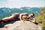 woman laying on a summit rock