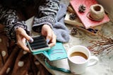 Girl holding her smartphone in her hands next to a cup of coffee.