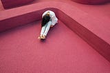 Lonely person with head down on knees in abstract red environment