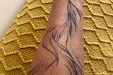 On my forearm is a tattoo that has different shades of purple and blue. It’s an abstract design that some say looks like feathers, waves, and seaweed and has aspects of the moon, music and dance drawn throughout. It’s an intuitive tattoo design.