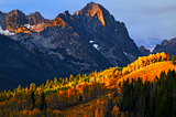Picture of the sunset illuminating the fall colors and casting shadows on the valley at the Sawtooth Mountsin in Idaho.