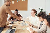 Two men shaking hands during a team office meeting.