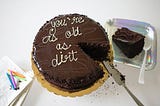 Chocolate birthday cake with the saying you’re as old as dirt written on it with icing.