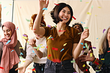 Action shote of mixed age multiethnic women celebrating by dancing with ticker tape. Credit: Southworks Creative Ltd