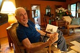 Joe Simboli holds a photo of himself in a WWII tank.