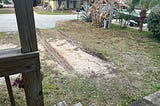 An empty driveway with deep muddy tire drag marks.