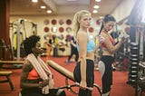 Three girls training in the gym with weights in their hands