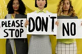 Three women with serious expressions holding signs that say “Please stop,” “Don’t,” and “No”