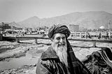 An old Afghan man smiles into the camera by The Kabul River, Afghanistan.