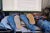 The crochet slippers I am working on with the accompanying piece on the screen. By the Author.