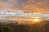 A fantastic sunrise with blue skies sandwiched between the ground and grey clouds.