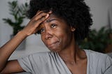 A picture of a young black woman who is sad and looks like she is on the verge of tears.