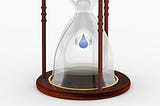 A drop falls in an hourglass. Photo illustration by Buddha Elemental 3D on Unsplash