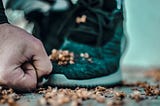 Man’s fist on ground with athletic shoe in background