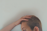 Woman with short hair holds her head in her hand
