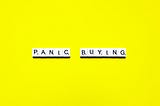 Panic Buying words spelled on a bright yellow background — depicting psychological traps of online shopping