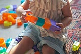 Child playing with colourful plastic blocks.