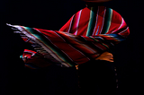 A Mexican dancer in movement, wearing a poncho and a sombrero