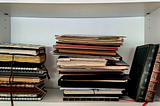 The author’s three notebook stacks on a white shelf.