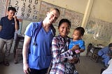 Nurse poses for photo with mom and baby in arms.