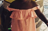 A young girl in a market stares upward into the camera.