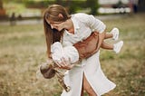 Mother with little daughter playing in a summer park