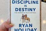 Discipline Is Destiny Book Cover in hand with a painted nail.