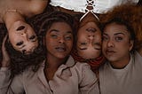 Four Black womxn with natural hair in nuetral colors