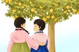 Two women in Korean hanboks stand in front of an orange tree looking at each other with one woman’s arm around the other.