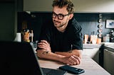 A man leaning on a table with a laptop.