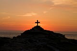 A cross on a hill at sunset or sunrise