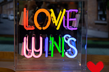 neon rainbow of colors sign — Love Wins — with red heart in bottom right corner