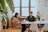 Two people sitting at a home desk working on their laptops