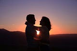 A couple about to kiss as the sky turns purple during sunset