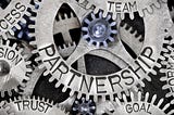 Metal coges interlinking with words ‘partnership’ ‘trust’ ‘goal’ ‘team’ etched on them