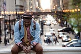 A man sits in a city looking sad