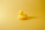 A yellow plastic duck on a yellow background.