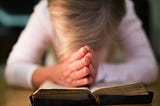 A woman prays over a bible.