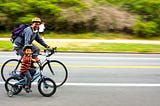 Dad and kid riding bikes in the park.