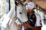 Timmy Dutta stands with a white polo pony, wearing a Zarasyl hat and holding a tube of Zarasyl.