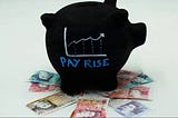 A picture of a black piggy bank with a upwards trending graph on the side and the words “pay rise” on top of a variety of Australian bank notes.
