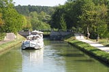 A renovated barge floats on the serene water of the Nivernais Canal in Burgundy, France.