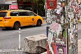 Zohran Mamdani picture in New York City with a yellow cab driving by.