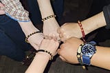 A bunch of hands with a friendship bracelet