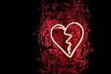 A glowing light red neon heart displayed against a dark red background.